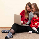 Front view of woman and children with down syndrome looking at laptop