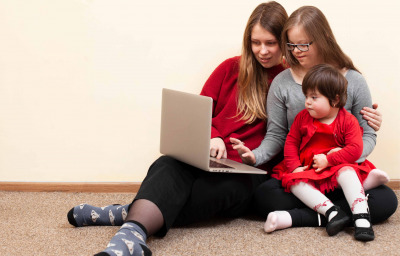 Front view of woman and children with down syndrome looking at laptop
