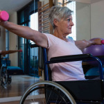 Senior woman in wheelchair performing exercise with dumbbell