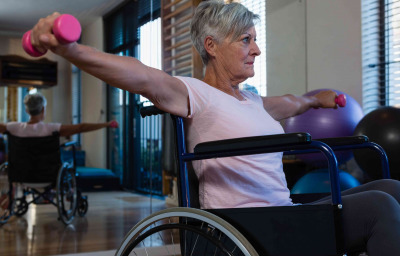 Senior woman in wheelchair performing exercise with dumbbell