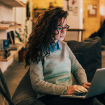 Woman with glasses using laptop in modern interior