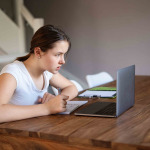 Teenager girl studying online at home looking at laptop