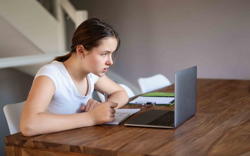 Teenager girl studying online at home looking at laptop