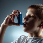 Portrait of a boy using an asthma inhaler