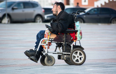 Man in electric wheelchair moving along the city street