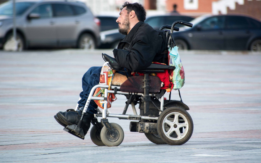Man in electric wheelchair moving along the city street