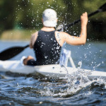 athlete at rowing kayak on lake during competition.splashing water in foreground