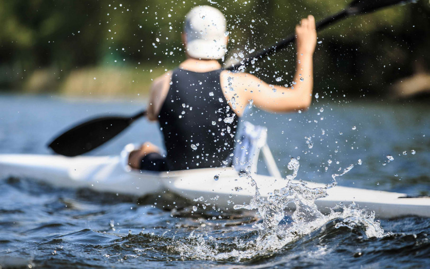 athlete at rowing kayak on lake during competition.splashing water in foreground