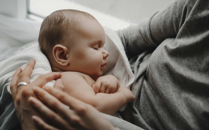 Charming newborn boy sleeps on mother's arms