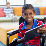 boy in wheelchair using digital tablet