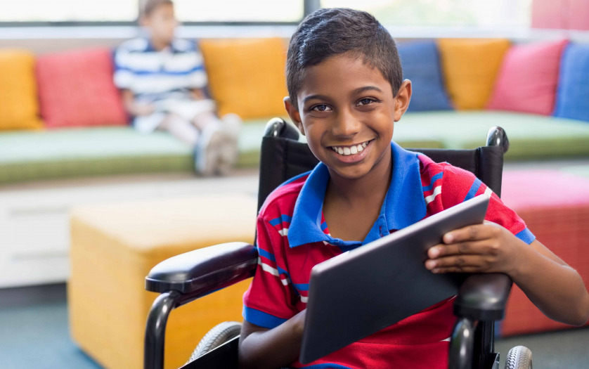 boy in wheelchair using digital tablet