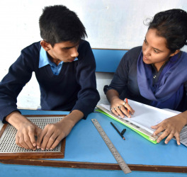 A blind Indian student giving examination to the teacher in a class room