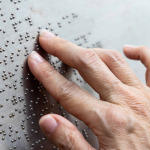 Finger reading braille tactile on public park message board