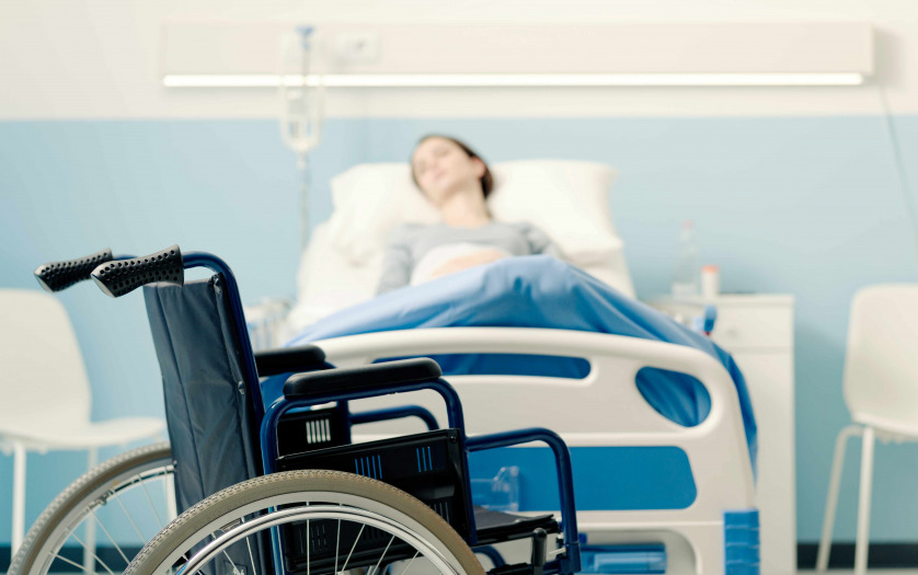 Hospitalized patient lying in bed and wheelchair in the foreground