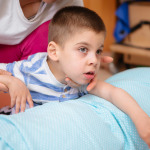 Little kid with cerebral palsy has musculoskeletal therapy by doing exercises