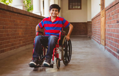 Boy sitting in wheelchair in school corridor