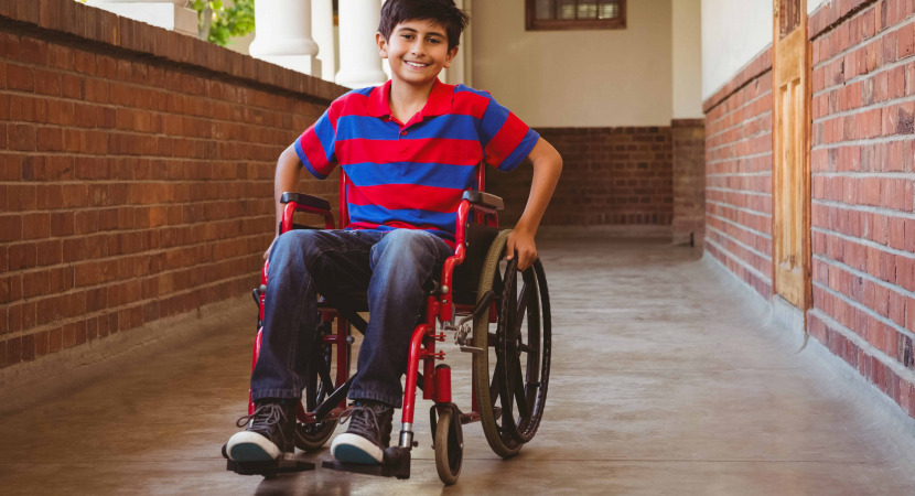 Boy sitting in wheelchair in school corridor