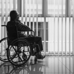 man in wheelchair while staring out of a window