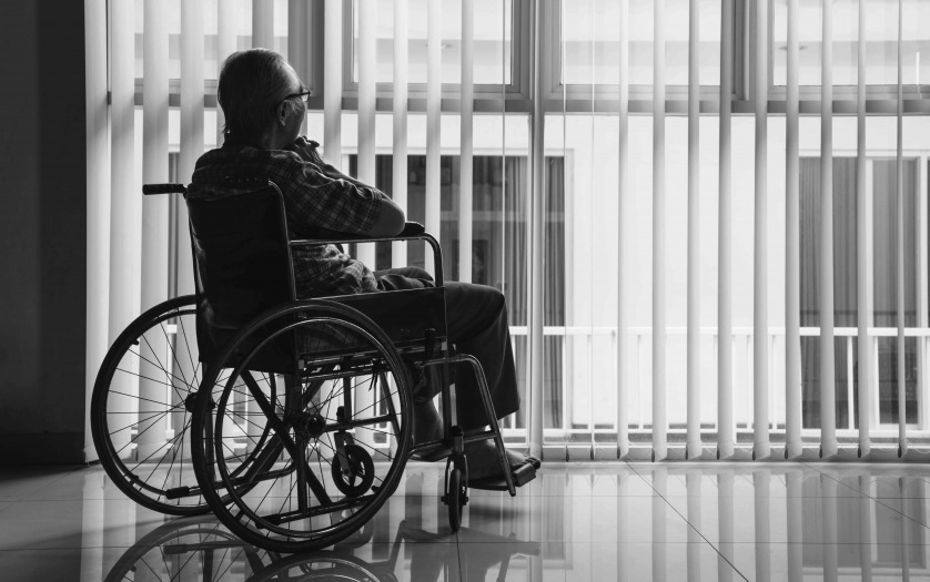 man in wheelchair while staring out of a window