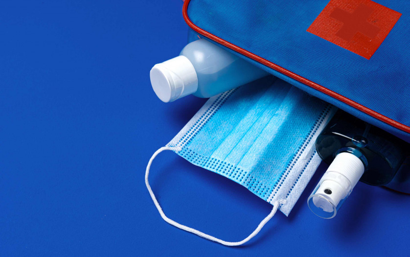 First aid kit with mask and sanitizer on blue background
