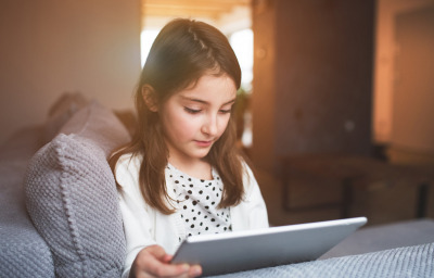 A happy small girl with tablet at home.