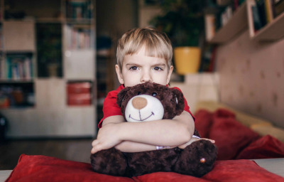 Little boy hugging his teddy bear with sad feelings
