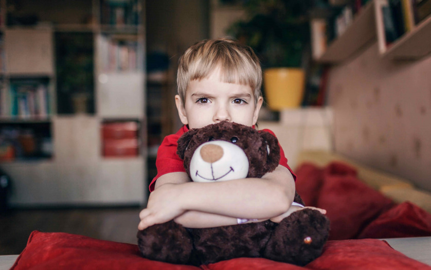 Little boy hugging his teddy bear with sad feelings
