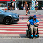 man in a wheelchair at a pedestrian crossing