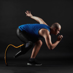Side view of paralympic sportsman in sports clothing and with prosthesis instead of leg running over black background