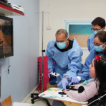 Microsoft's Yaron Galinsky with ALYN's Dr. Maurit Beeri and Arie Yekel-Melamed are seen helping a patient play 'Forza Horizon 4' on the Xbox One using an Xbox Adaptive Controller.