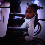 Schoolgirl looking at camera and sitting at desk in classroom of elementary school