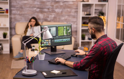 Creative videographer editing a movie on computer from home