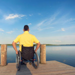 man in a wheelchair watching the sea in summer