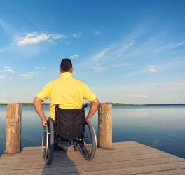 man in a wheelchair watching the sea in summer