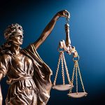 Bronze figurine of a blindfolded Lady Justice with her scales representing law and order on a blue background with copy space