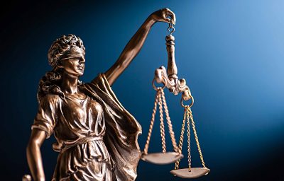 Bronze figurine of a blindfolded Lady Justice with her scales representing law and order on a blue background with copy space