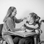 A disabled child in a wheelchair being cared for by a voluntary care worker.