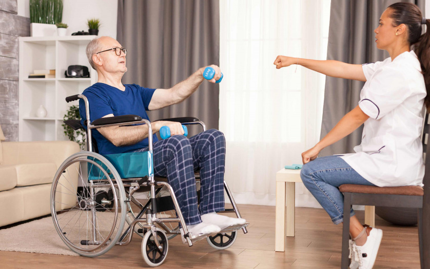 old man in wheelchair with medical worker in nursing care home assistance