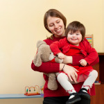 Woman holding smiley child with down syndrome