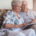 old woman sitting with her husband and using digital tablet.