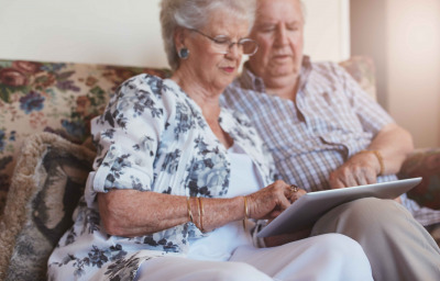 old woman sitting with her husband and using digital tablet.