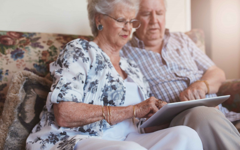 old woman sitting with her husband and using digital tablet.