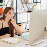 teenage girl watching online webinar on computer at her desk at home