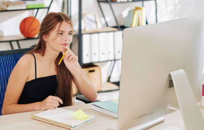 teenage girl watching online webinar on computer at her desk at home