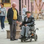 Close up of two senior men while one is in the wheelchairs and driving in the street of Vinkovci, Croatia.