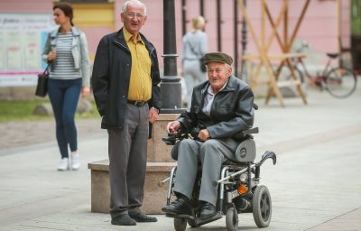 Close up of two senior men while one is in the wheelchairs and driving in the street of Vinkovci, Croatia.