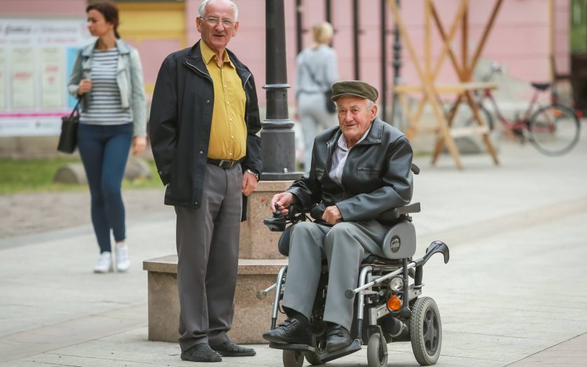 Close up of two senior men while one is in the wheelchairs and driving in the street of Vinkovci, Croatia.