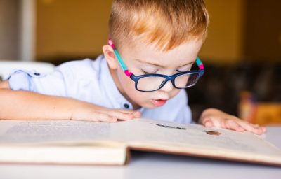Boy with down syndrome with big glasses reading book