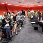 Students sit facing camera in a modern university classroom