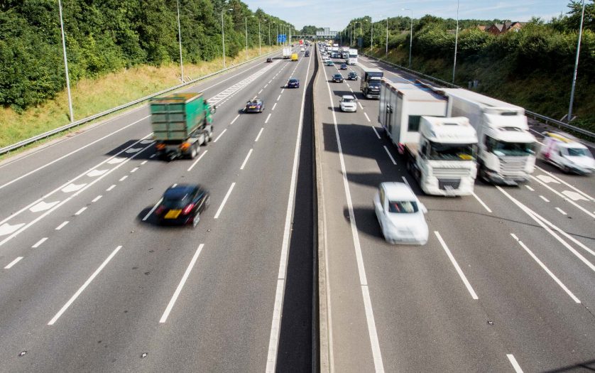 An aerial view of a busy UK motorway or highway with speeding cars and traffic and copy space